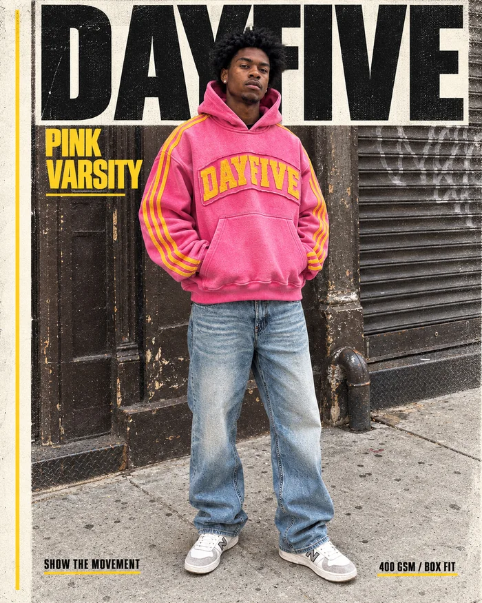 Pink varsity hoodie campaign poster against an urban storefront.
