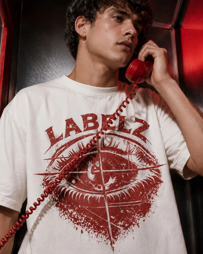 Model in a white graphic T-shirt holding a red telephone handset.