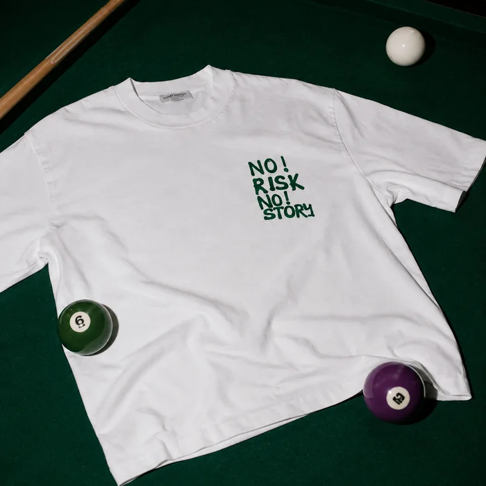 White T-shirt laid flat on a pool table.
