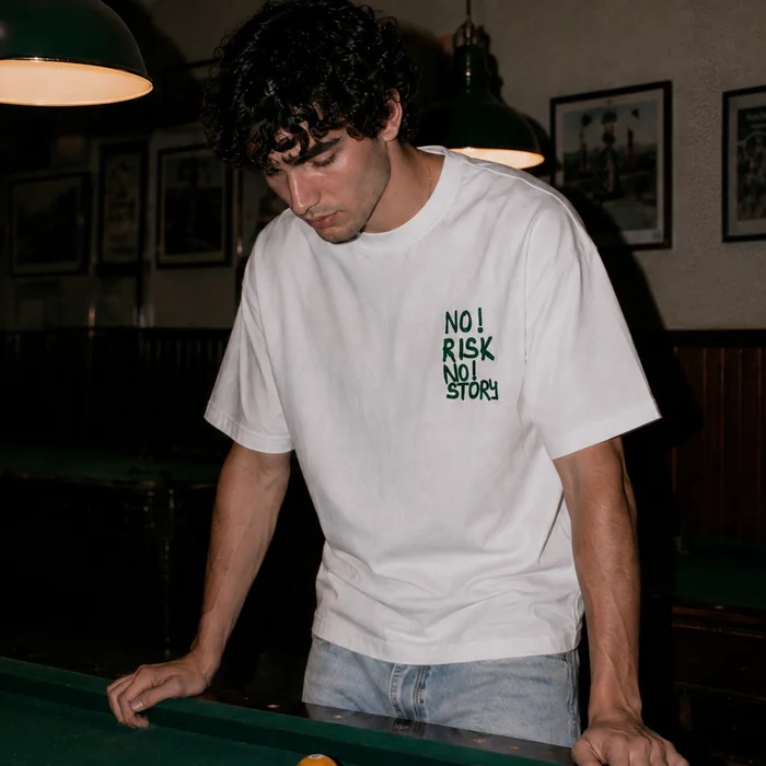 Close view of a man in a white T-shirt by a pool table.
