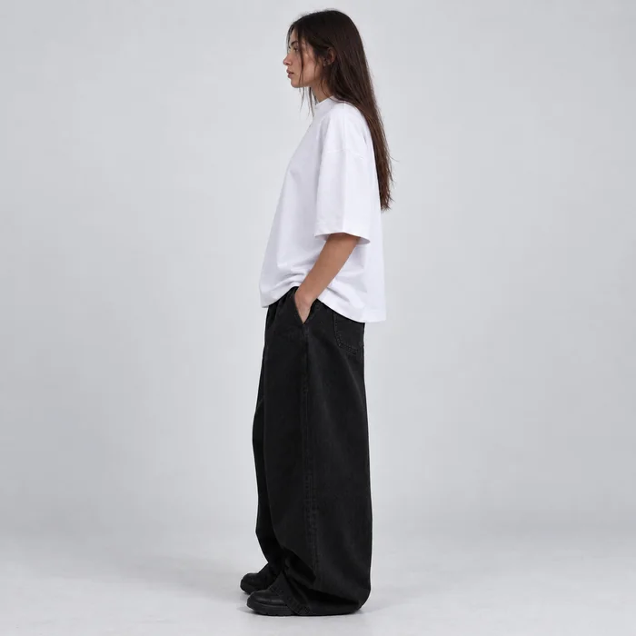 Full-length side view of a woman in a white T-shirt in a studio.