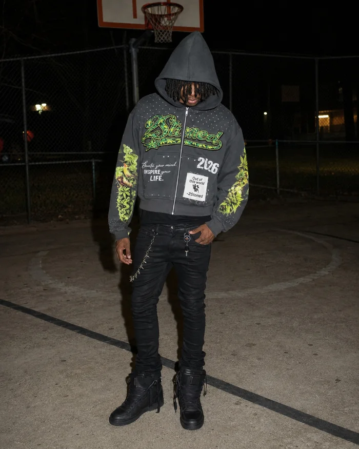 Man in a dark hoodie with green graphics on a basketball court.