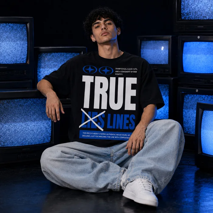Man wearing a black and blue graphic T-shirt among vintage televisions.